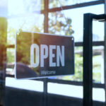 Open sign hanging front of small business building.